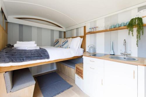 um pequeno quarto com uma cama e um lavatório em Gorgeous Shepherds Hut - Walk to Beach & Pub em West Wittering