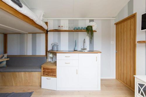 cocina con armarios blancos y lavabo en una habitación en Gorgeous Shepherds Hut - Walk to Beach & Pub, en West Wittering