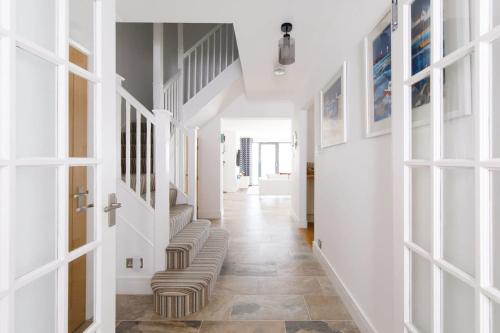 a hallway with white walls and a staircase with chairs at The Sea House - Ultimate Seafront Living & Sunsets in Selsey