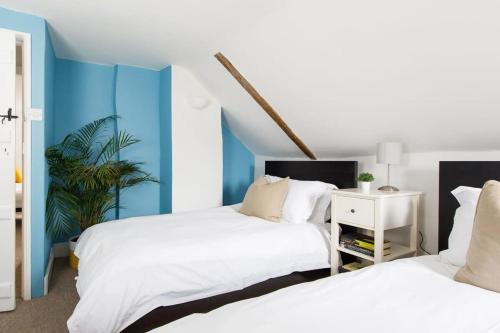 Charming three-bedroom central townhouse في شيشستر: غرفة نوم بسريرين وجدار ازرق