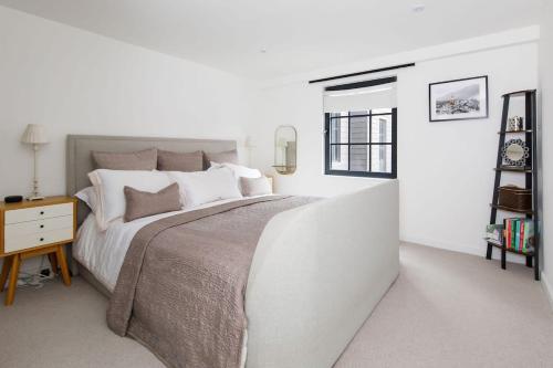 a white bedroom with a large bed and a table at Stylish City Centre Apartment with Sauna in Chichester
