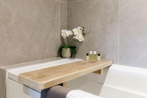 a bathroom with a wooden bench next to a bath tub at Stylish City Centre Apartment with Sauna in Chichester