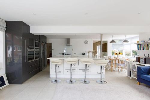 a kitchen with a white counter and stools in it at Secluded rural retreat close to beach - sleeps 12 in Earnley