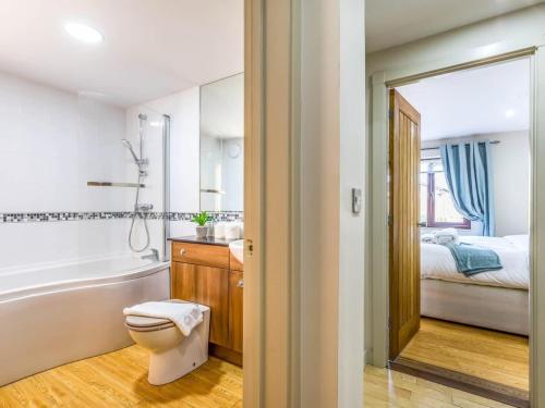 a bathroom with a toilet and a tub and a bed at Modern Ground Floor Apartment with Parking in Fishbourne