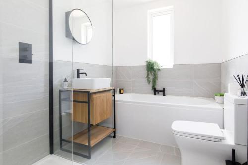 a bathroom with a sink and a tub and a toilet at Stylish 2 Bed City Stay in Chichester