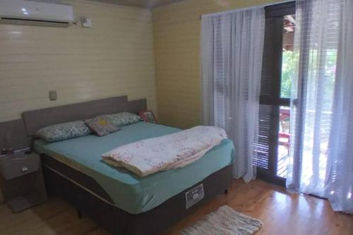 ein Schlafzimmer mit einem Bett in einem Zimmer mit einem Fenster in der Unterkunft Sítio em área rural, ao pé da Serra Gaúcha. in Três Coroas