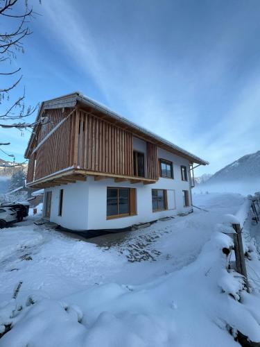 a house is covered in snow with a fence at Garten Chalet in Bayrischzell