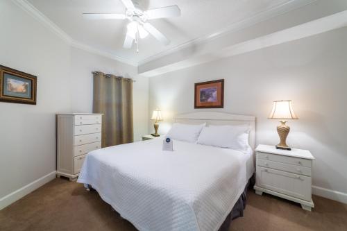 ein Schlafzimmer mit einem weißen Bett und zwei Nachttischen in der Unterkunft Phoenix on the Bay 1412 Waterfront Condo in Orange Beach