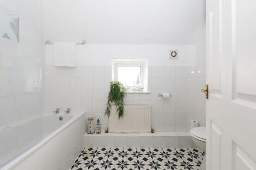 baño blanco con bañera blanca y aseo en Two-bed beachside apartment West Wittering, en West Wittering