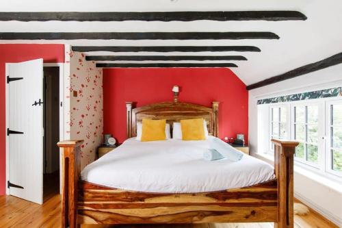 a bedroom with a wooden bed with red walls at Tranquil Luxe in Country Cottage in Bosham