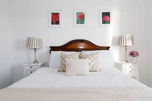 a white bedroom with a white bed with two lamps at Two Bed Seafront Escape in East Wittering in East Wittering