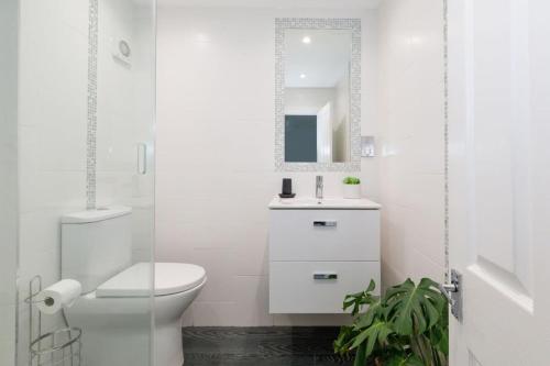 a white bathroom with a toilet and a mirror at Two Bed Seafront Escape in East Wittering in East Wittering