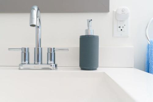 a soap dispenser sitting on a counter next to a sink at Sleek & Stylish Apt Steps From Bluebird Theater in Denver