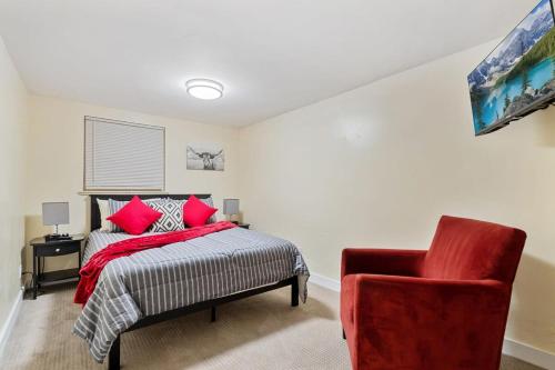 a bedroom with a bed and a red chair at Cozy & Spacious Apartment Steps From Regis in Denver