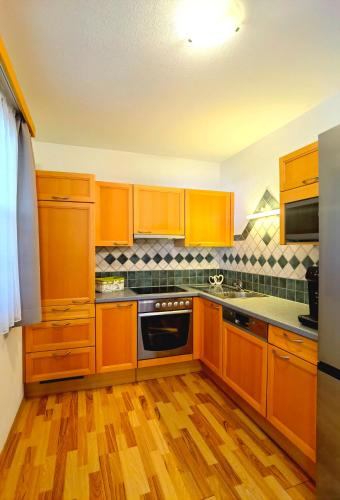 a kitchen with wooden cabinets and wooden floors at Appartement Fritzenwallner in Wagrain