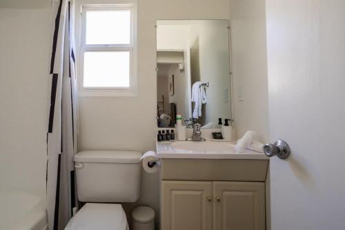 a bathroom with a toilet and a sink and a mirror at Sunny Modern Studio Close to LAX in Los Angeles