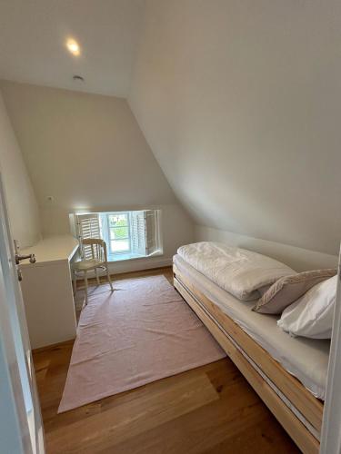 a small bedroom with a bed and a desk at Kapitänshaus von 1712 - neu saniert in Nieblum
