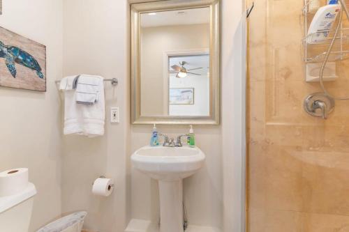 La salle de bains blanche est pourvue d'un lavabo et d'une douche. dans l'établissement Seaside Retreat Steps from Ocean And Restaurants, à Deerfield Beach