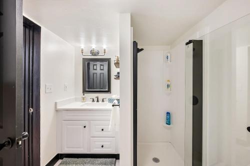 Baño blanco con lavabo y espejo en Charming & Updated Garden Level in Heart of Denver en Denver