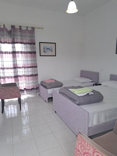 a room with three beds and a table and a chair at STUDIOS MONA in Agios Georgios