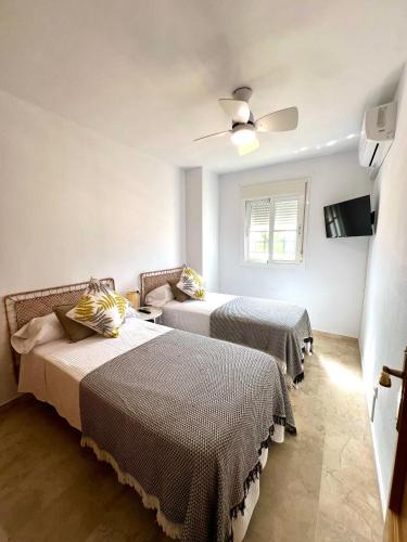 una camera da letto con due letti e un ventilatore a soffitto di Casa Baviera Golf & Beach a Caleta de Velez