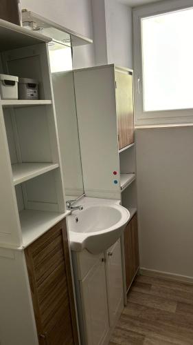 une salle de bain blanche avec un lavabo et un miroir dans l'établissement Maison de ville à 3 kilometre du centre de cognac , jacuzzi privée et disponible sur place, à Saint-Brice