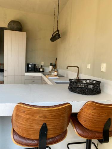 a kitchen with a counter and two wooden chairs at POLDER aan de Zeeuwse kust in Wemeldinge