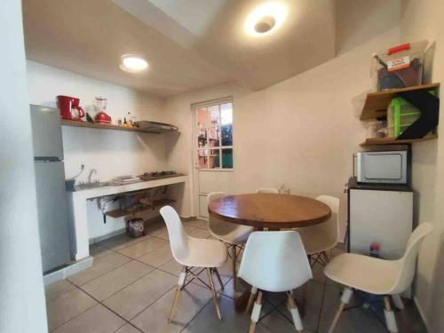 プエルト・エスコンディードにあるCasa de 3 recámaras en Bacochoのキッチン(木製テーブル、白い椅子付)