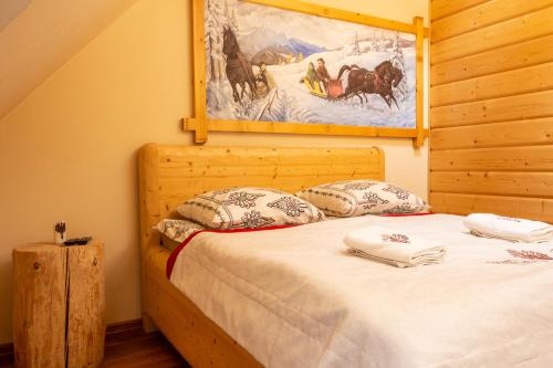 a bedroom with a bed with a painting on the wall at Poronin Mountain Apartments in Poronin