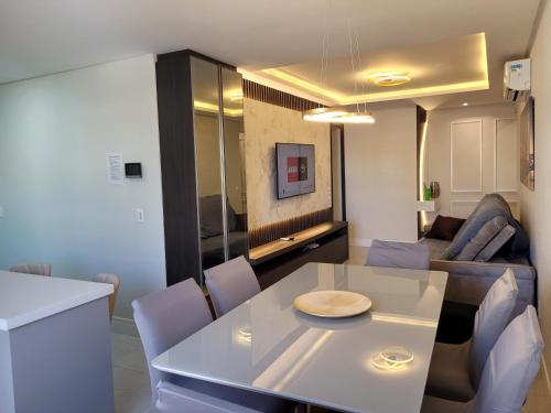 ein Wohnzimmer mit einem weißen Tisch und einer Couch in der Unterkunft Apartamento novo luxo, 2 suítes, piscina aquecida no condomínio, 1 quadra do mar, completo in Bombinhas