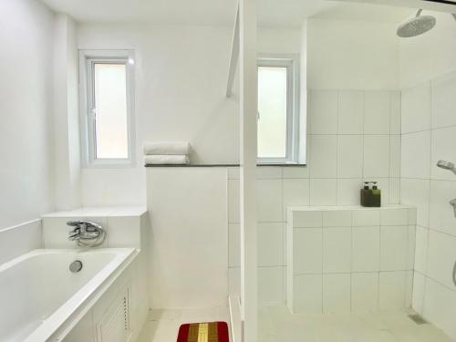 a white bathroom with a shower and a sink at Villa Nap Dau Crown Private Pool Villa Phuket in Ban Klang