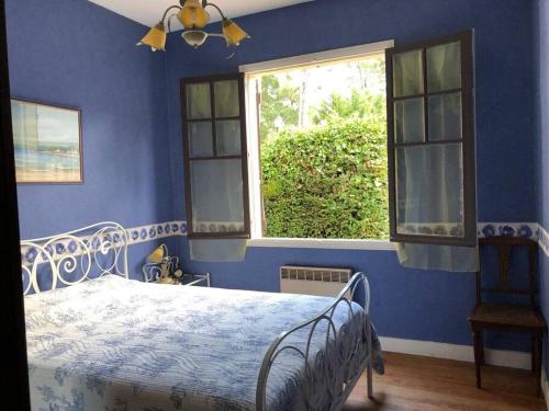 une chambre bleue avec un lit et une fenêtre dans l'établissement La Chaumière, à La Tremblade