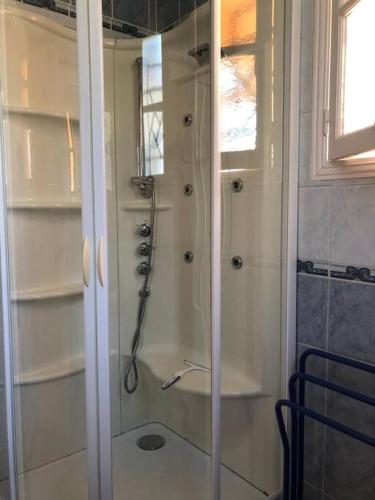 une douche dans une salle de bain avec une porte vitrée dans l'établissement La Chaumière, à La Tremblade