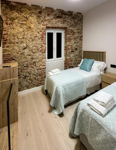 a bedroom with two beds and a brick wall at El Reloj De La Villa in Valdefuentes
