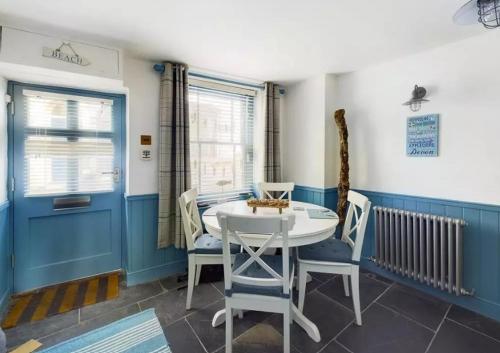 uma sala de jantar com uma mesa branca e cadeiras em 2 Bed cottage in a fantastic sea front setting em Appledore