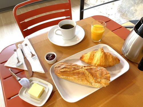 a table with a plate of pastries and a cup of coffee at Le Relais de 40 Sous in Aubergenville