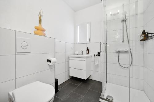 ein weißes Bad mit einer Dusche und einem WC in der Unterkunft Casa Oasis I: Modern, Nespresso & Thermennähe in Bad Füssing