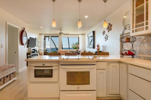 una cocina con armarios blancos y una gran isla de cocina en Poipu Makai E1, en Koloa