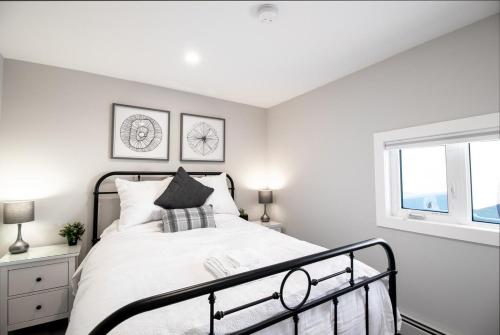 a bedroom with a bed and two windows at NN - Flats on 4th #3 - Downtown 1-bed 1-bath in Whitehorse