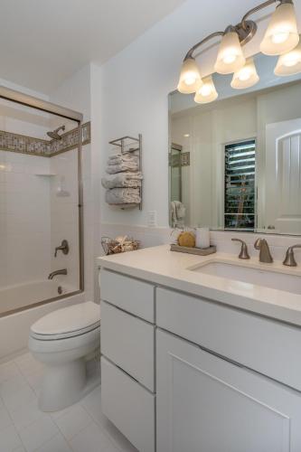 a bathroom with a toilet and a sink and a mirror at Poipu Makai E1 in Koloa