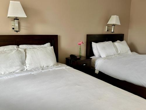 two beds in a hotel room with white sheets at Blowing Rock Inn in Blowing Rock