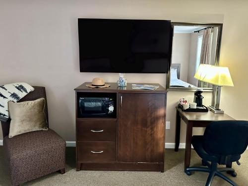 a room with a tv and a chair and a desk at Blowing Rock Inn in Blowing Rock