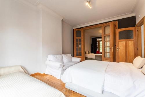 - une chambre blanche avec 2 lits blancs dans l'établissement 3 bedrooms apartement with enclosed garden and wifi at Bruxelles, à Bruxelles