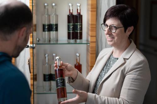 a woman holding a bottle of wine in front of a man at Hotel Garni Thermenglück in Unterlamm