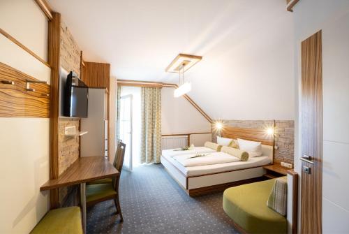 UnterlammにあるHotel Garni Thermenglückのベッドとデスクが備わるホテルルームです。