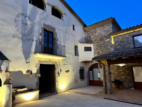 a white building with a door and a balcony at Masia Can Viver - Olive oil tourism B&B in Bigues i Riells