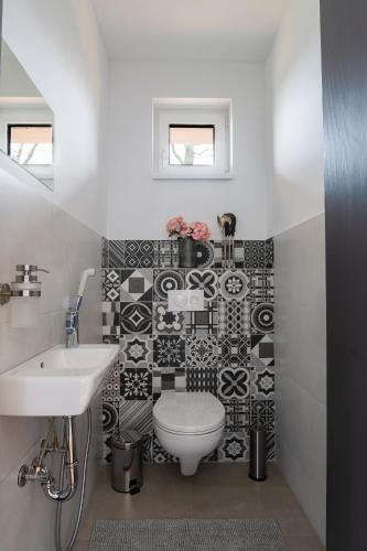 a bathroom with a white toilet and a sink at Tölgyes Villa in Kőszeg