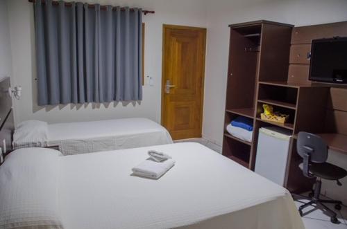 a room with two beds and a desk and a tv at Ville Park Hotel in Ourinhos