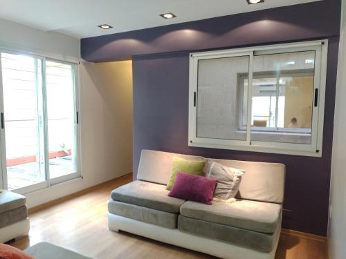 un soggiorno con un divano e due finestre di Experimenta la automatizacion: Departamento inteligente a Santiago del Estero