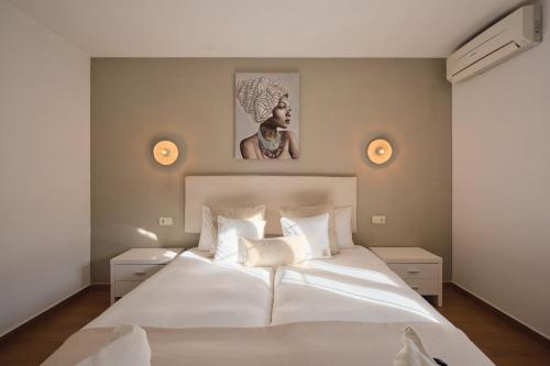 a bedroom with a large white bed with a picture on the wall at Villa B&M Experience in Sant Francesc de s'Estany